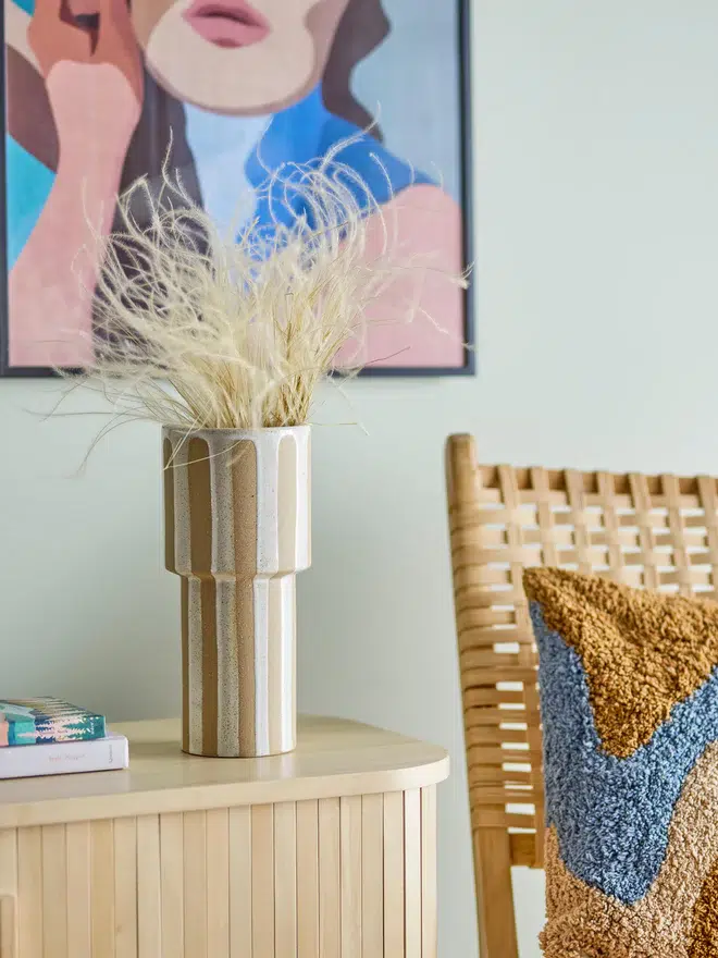 vase beige à rayures, un cadre bleu qui représente le portrait d'une femme
